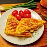 eto chaffwich sandwich triangles stacked on a plate with fresh tomatoes and herbs.