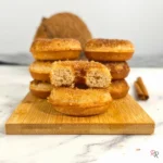 Stack of keto cinnamon sugar cottage cheese donuts made with coconut flour, with one sliced donut showing the fluffy inside.