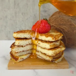Keto coconut flour cottage cheese pancakes topped with strawberry and drizzled with syrup