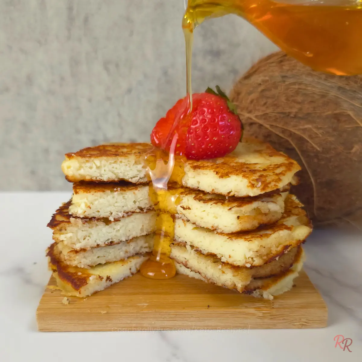 Keto coconut flour cottage cheese pancakes topped with strawberry and drizzled with syrup