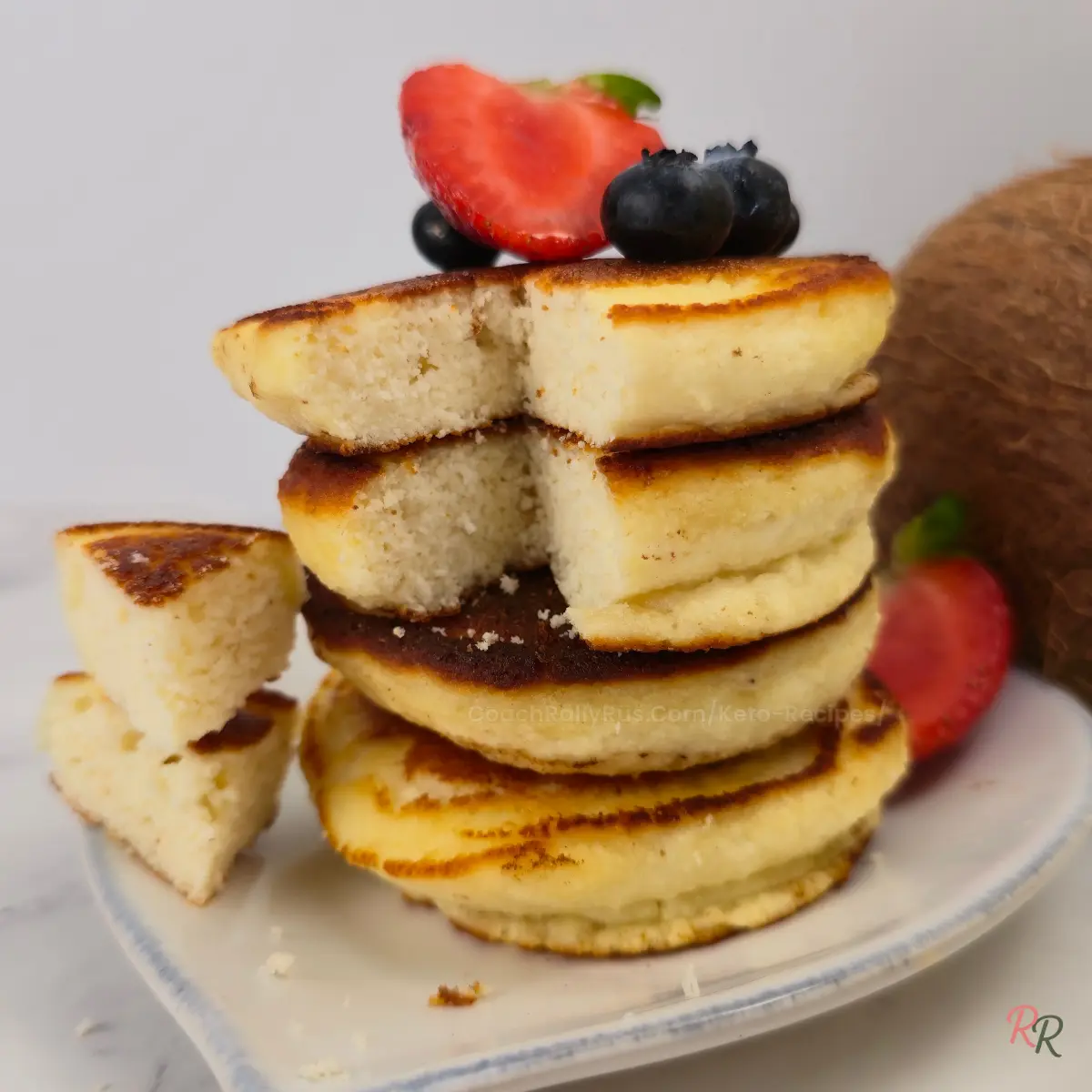Fluffy coconut flour pancakes cut open with strawberry and blueberries on top