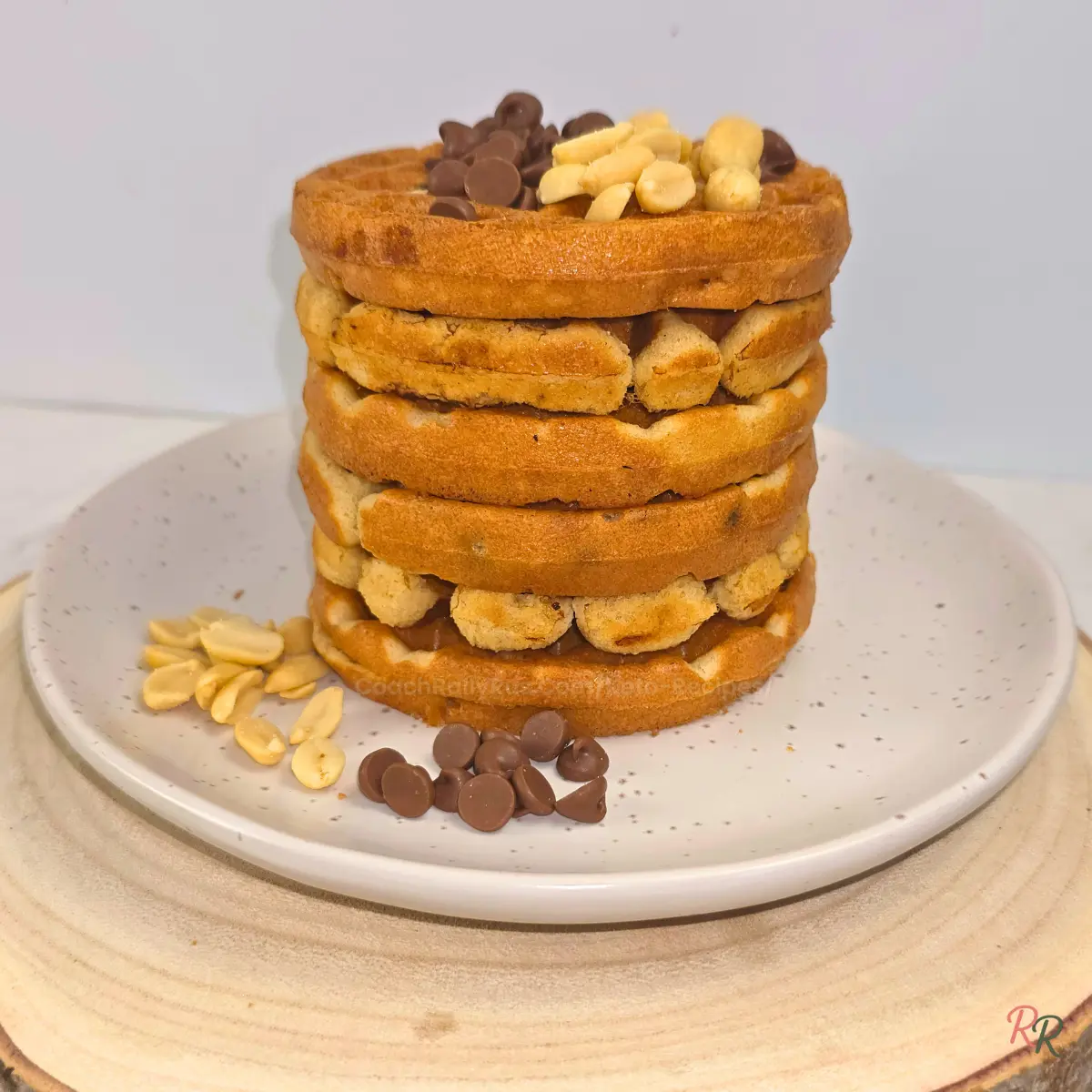 Stack of six keto cookie waffles filled with chocolate chips and peanuts on a speckled plate by Rally Rus