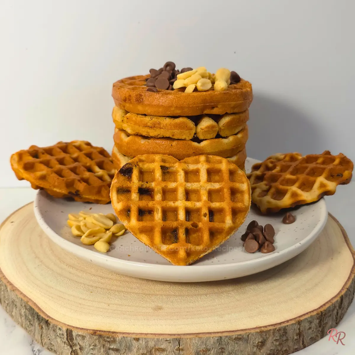 Plate of round and heart-shaped keto cottage cheese waffles with chocolate chips and peanuts by Rally Rus