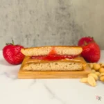 Close-up of a keto peanut butter and jelly pancake sandwich cut in half with strawberries and peanuts