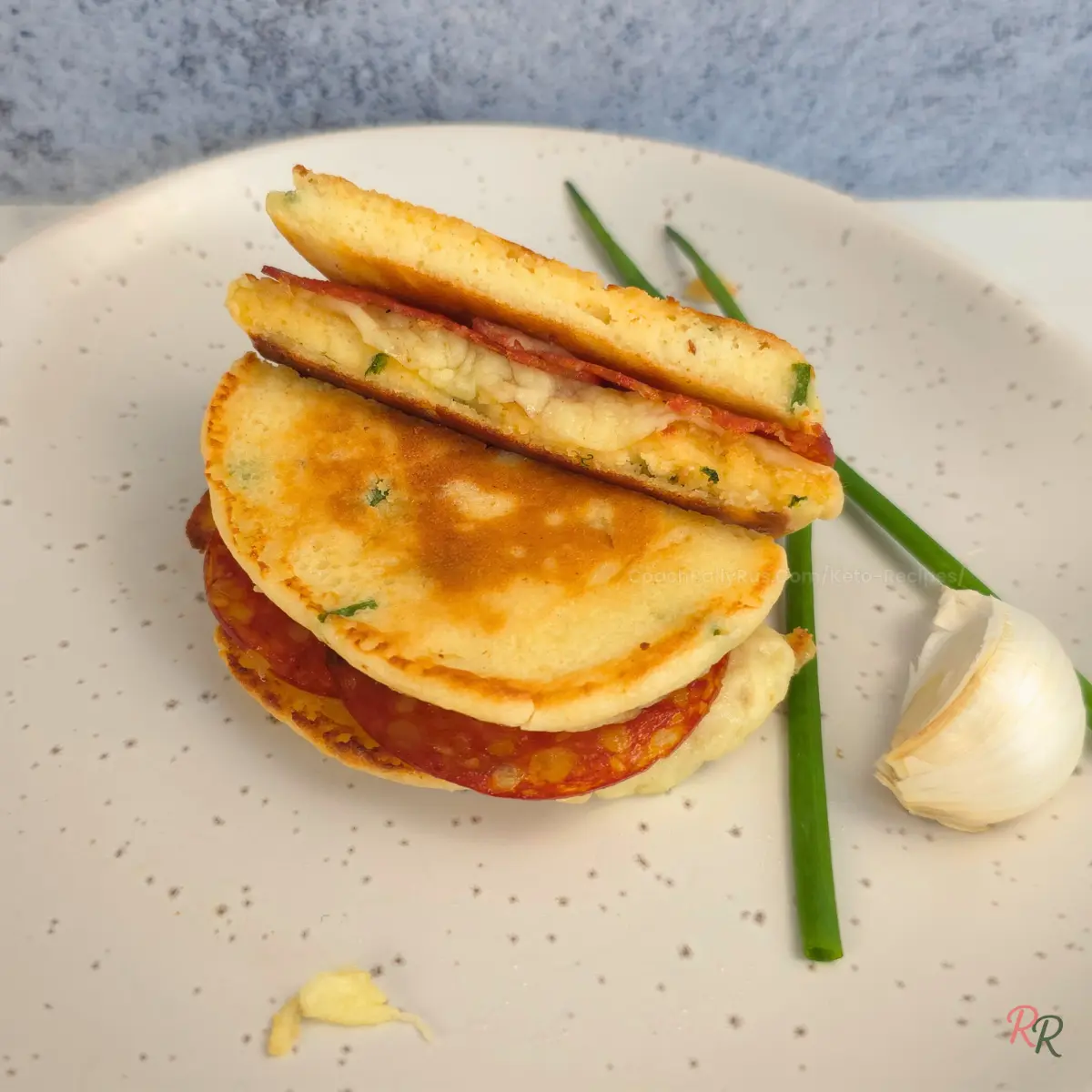 Sliced keto pancake sandwich showing melted cheese and pepperoni inside