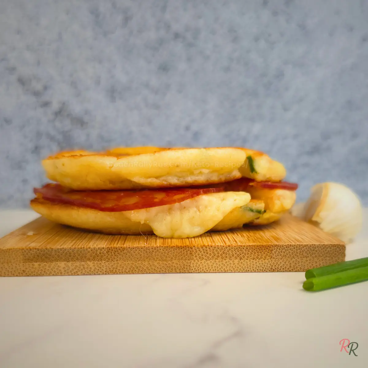 Stack of cheesy keto cottage cheese pancake sandwiches on wooden board