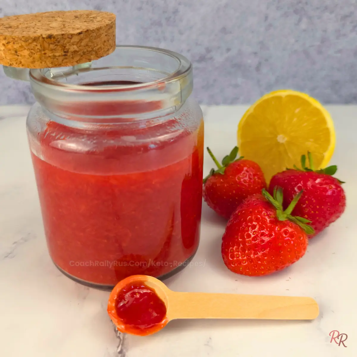 Top-down close-up of keto strawberry jam texture in a jar being covered with a cork lid.