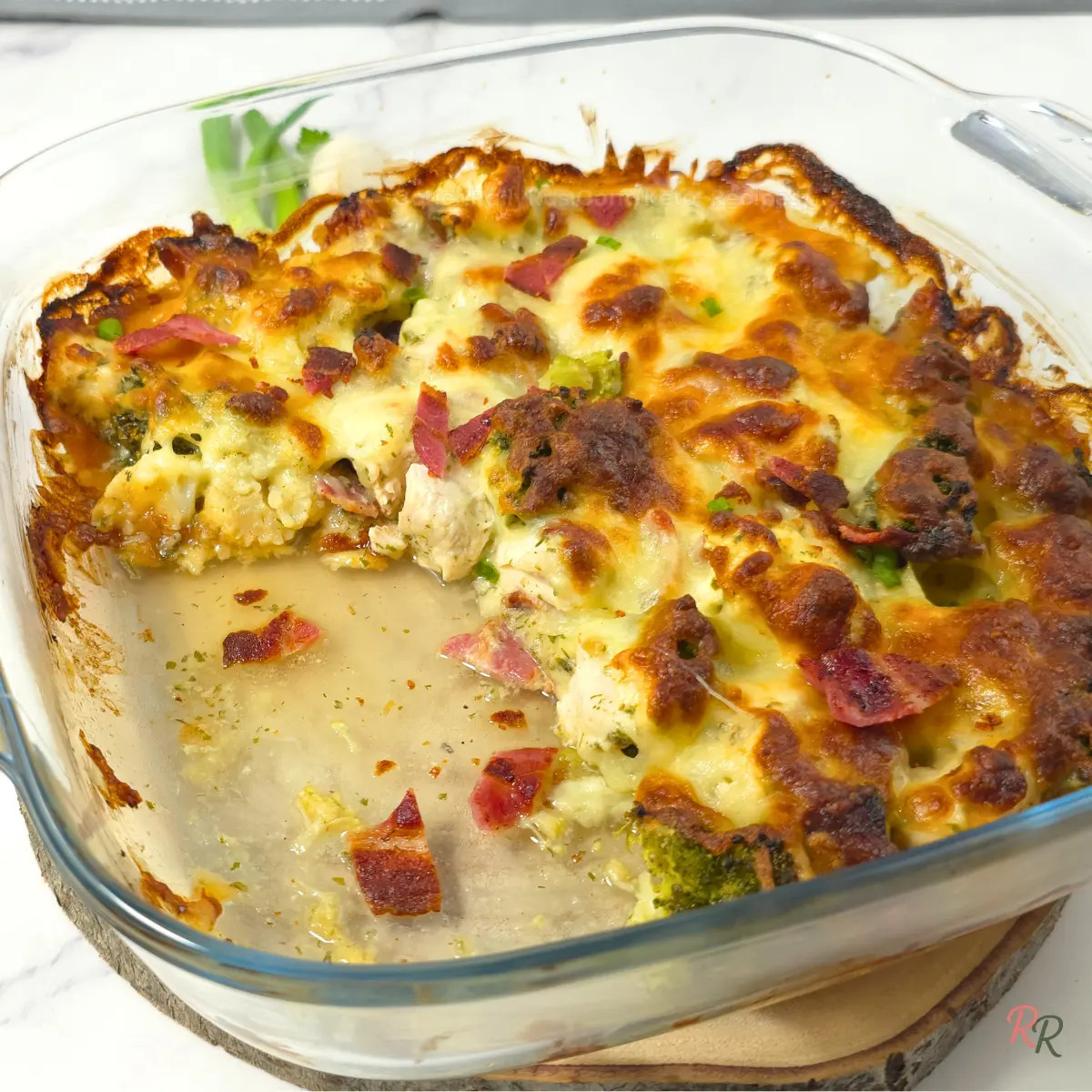 Cheesy Keto Chicken Bacon Ranch Casserole Cheesy baked Keto Chicken Bacon Ranch Casserole with bacon and broccoli in a glass casserole dish.