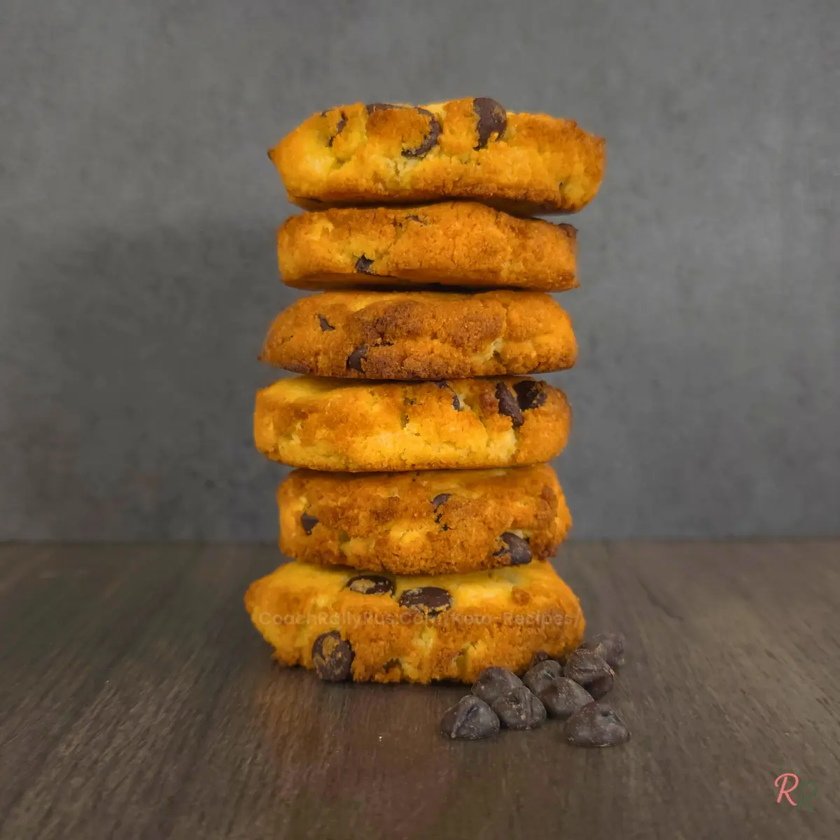 Crispy golden keto cookies stacked Stack of five crunchy keto chocolate chip cookies with chocolate chips scattered on the table