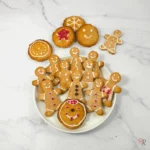 Low carb keto gingerbread cookies decorated as smiling cut-out people and festive round shapes with icing, on a white plate, perfect for Christmas or holiday baking – by Rally Rus