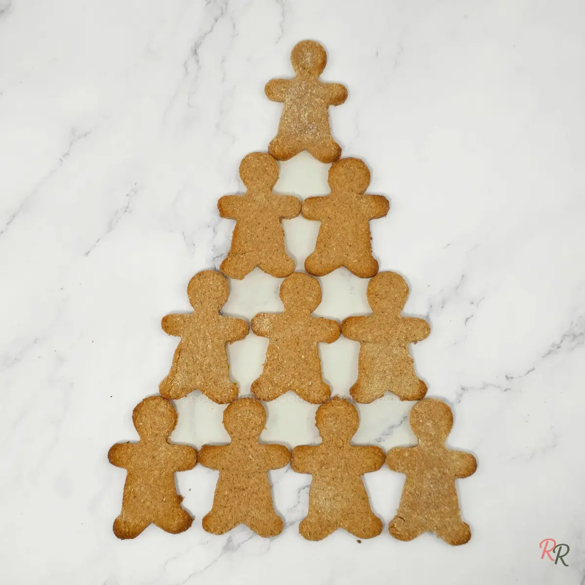 Undecorated gingerbread men arranged in a triangle tree shape