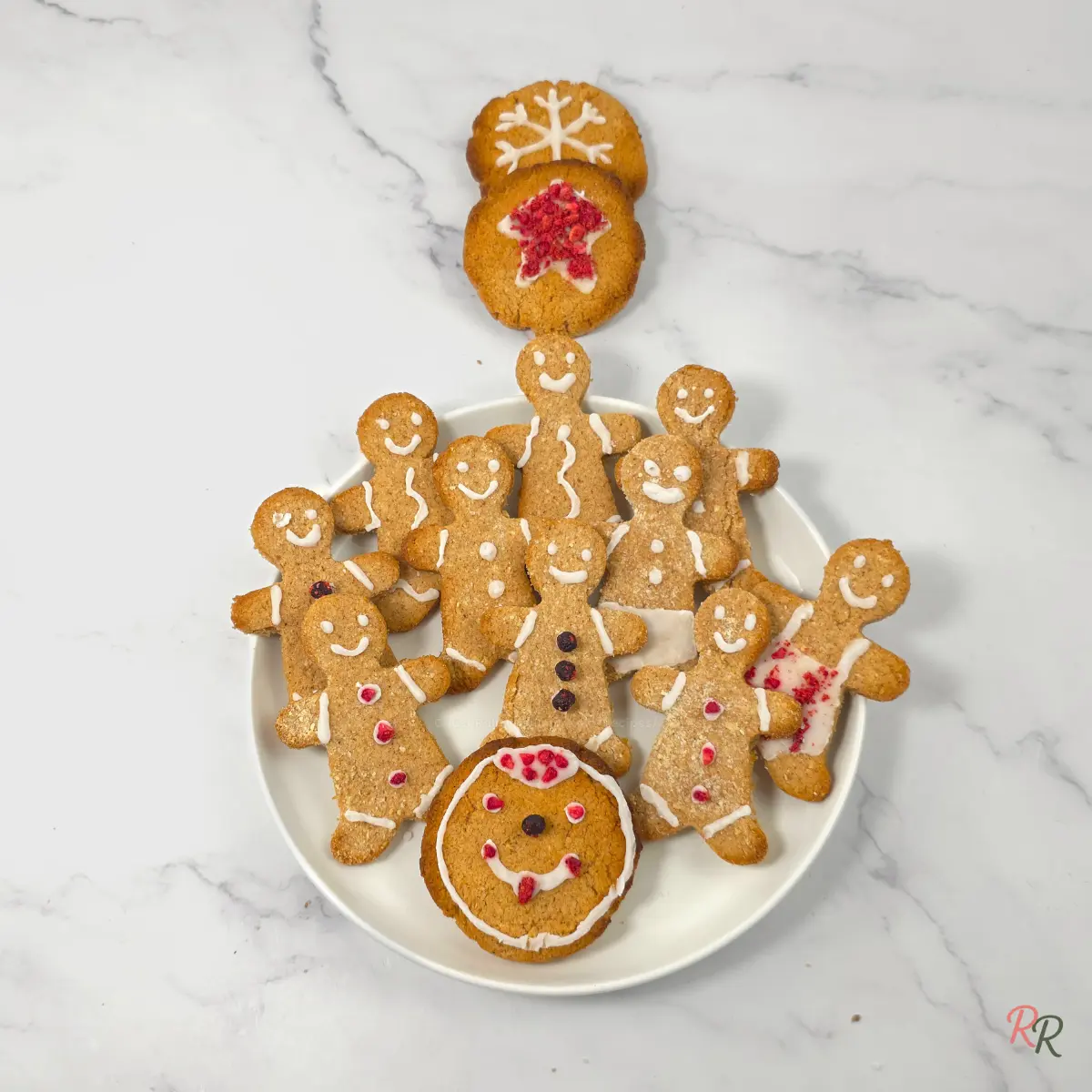 Plate of decorated keto gingerbread cookies with two round cookies above