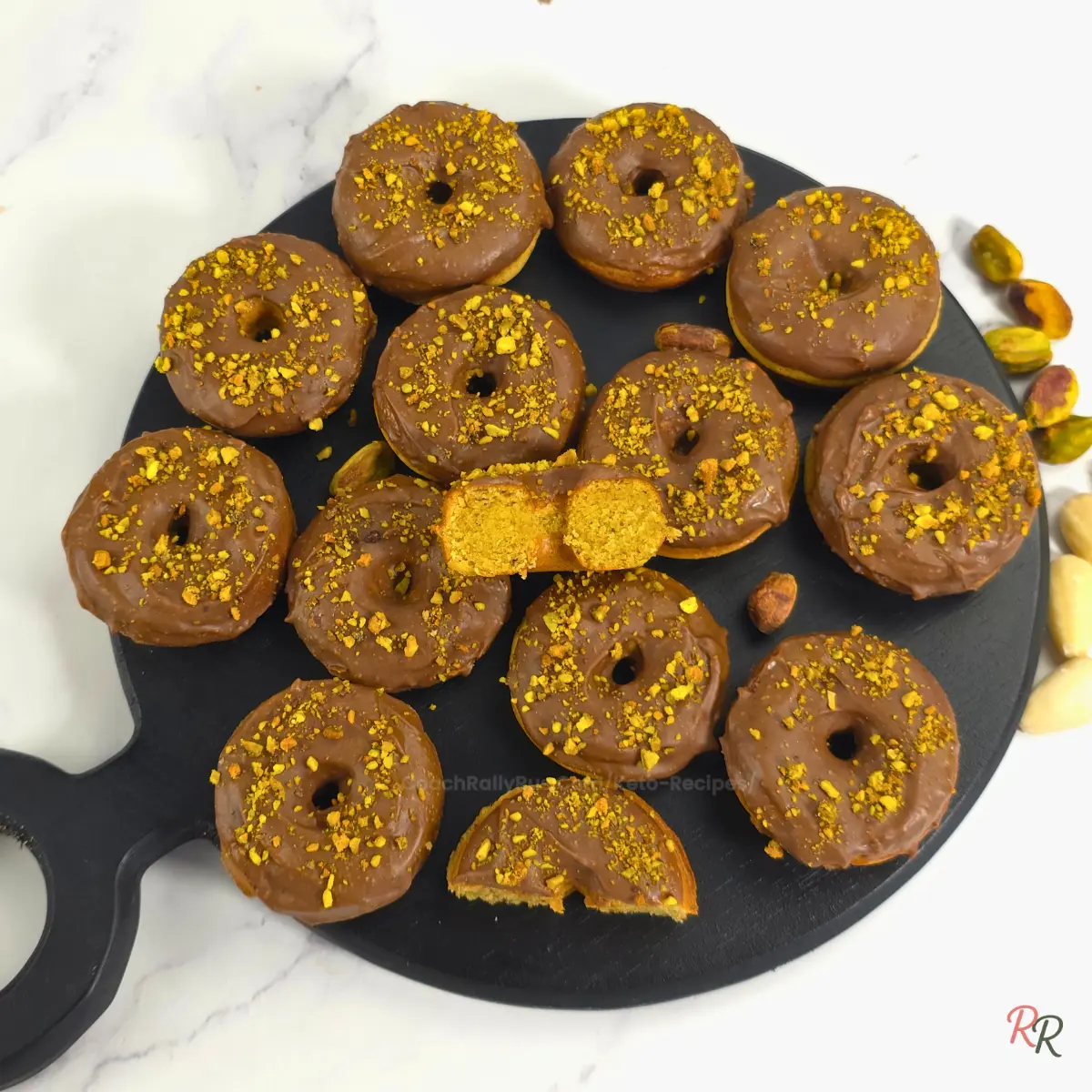 Keto pistachio cottage cheese donuts with almond flour displayed on a round black board.