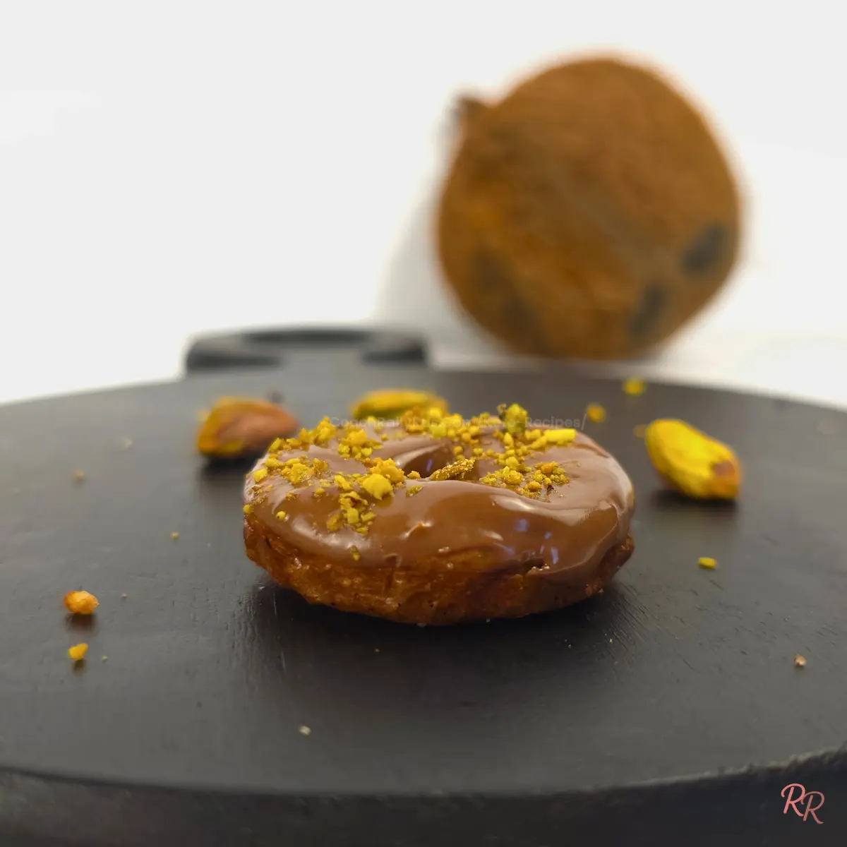 Close-up of a glazed keto pistachio cottage cheese donut topped with crushed pistachios
