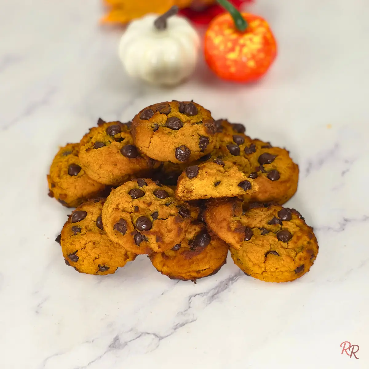 Pile of pumpkin chocolate chip cookies on marble surface