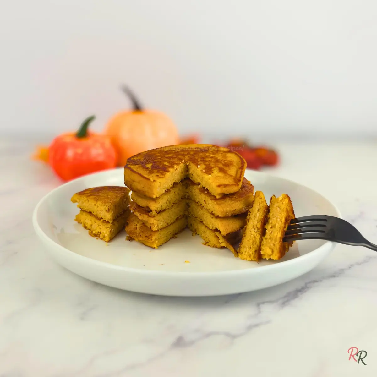 Sliced stack of pumpkin cottage cheese pancakes on white plate