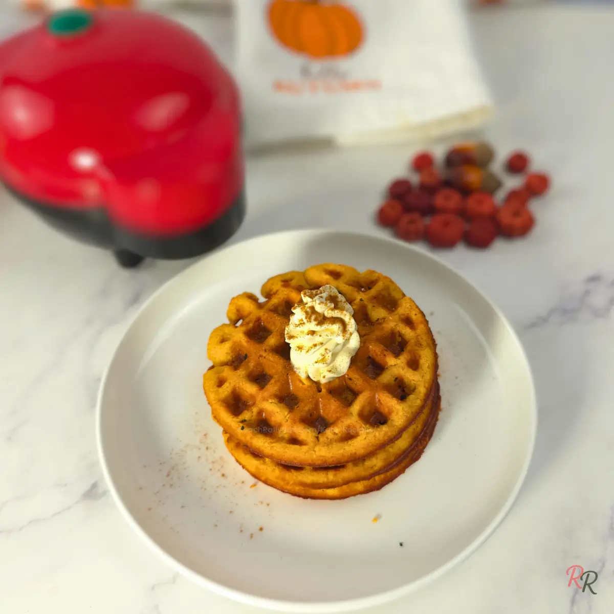 Keto pumpkin waffles made in a mini waffle maker with whipped cream on top