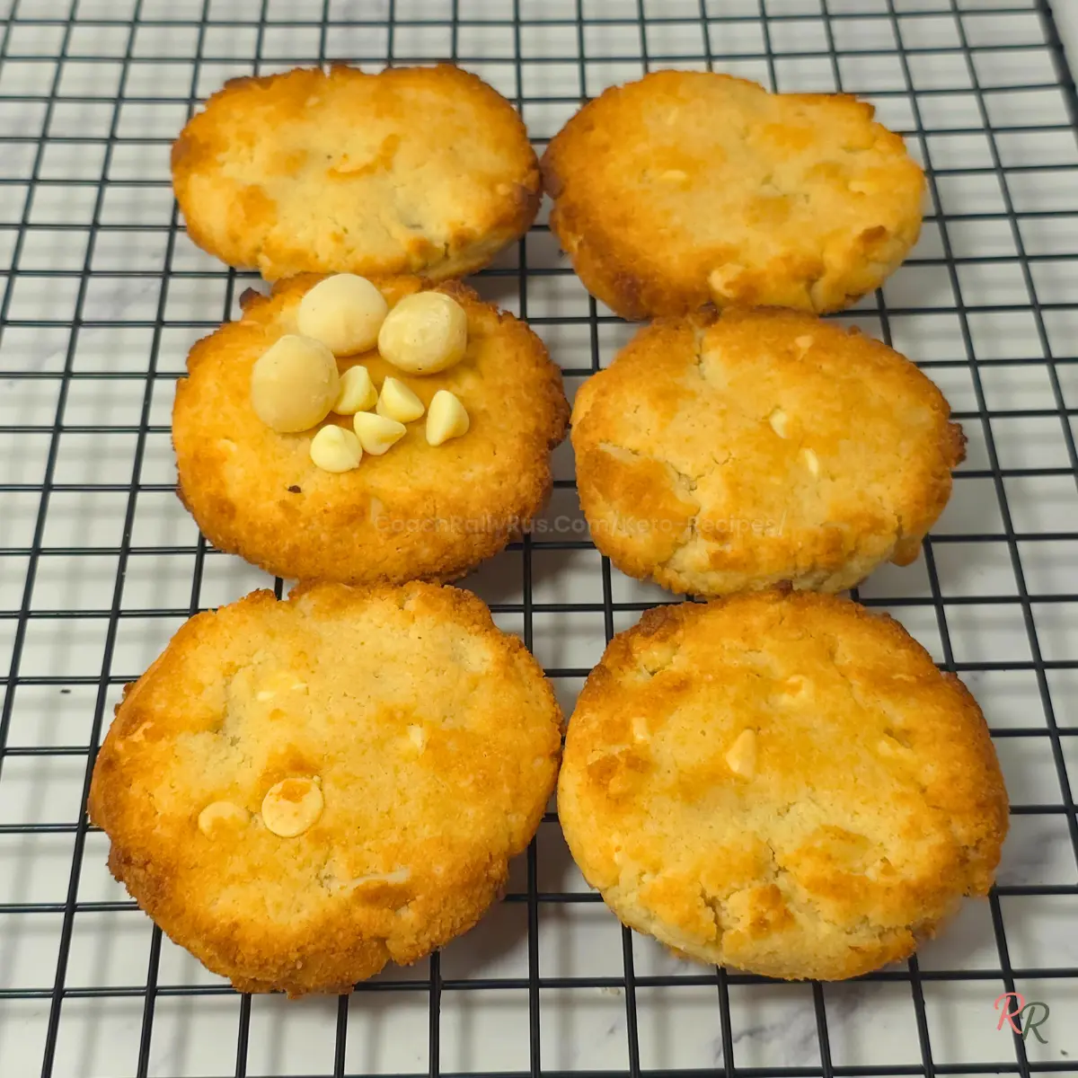 Keto White Chocolate Macadamia Cookies on Cooling Rack Keto white chocolate macadamia cookies cooling on a baking rack.