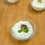 Bowl of whipped cottage cheese dip with dried oregano and fresh basil on top