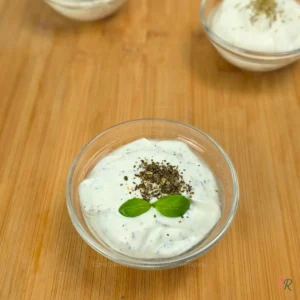 Bowl of whipped cottage cheese dip with dried oregano and fresh basil on top