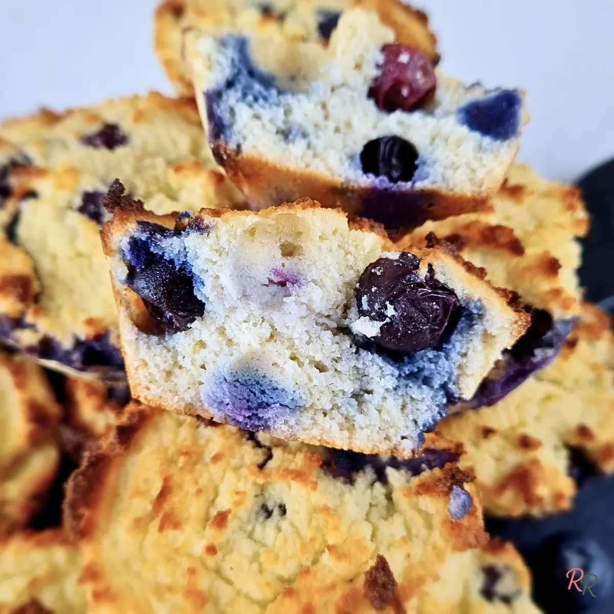 Inside view of a keto blueberry muffin with coconut flour, showing fluffy texture and whole berries.