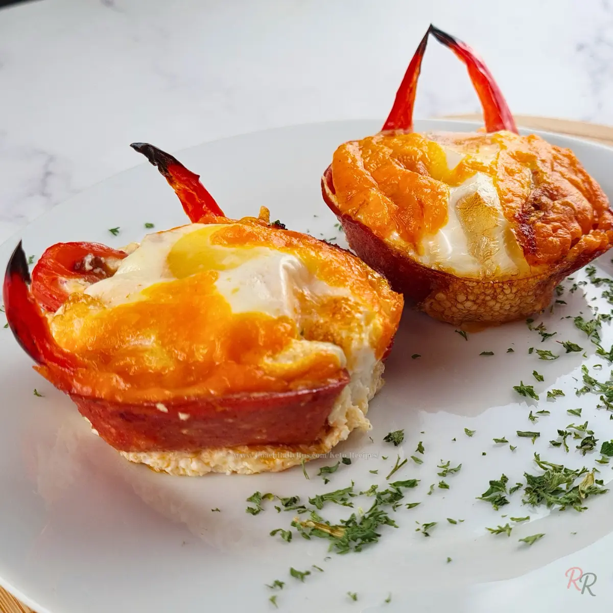 Keto Pepperoni Egg Muffin Cups with Pepperoni Keto egg muffins in pepperoni cups on a white plate with chopped herbs