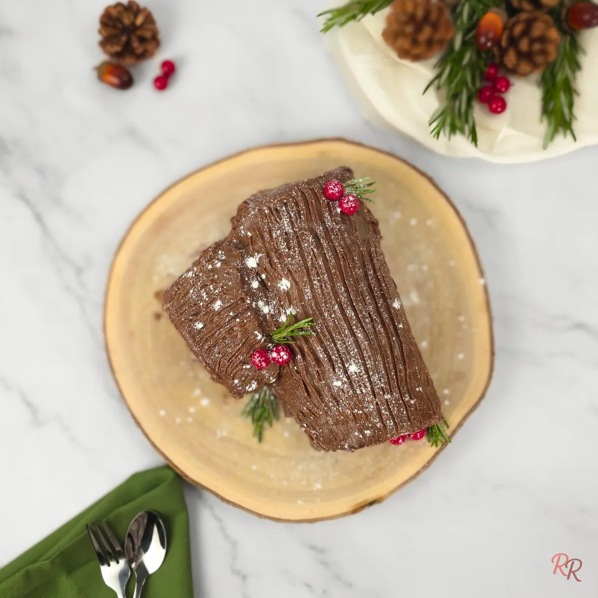 Overhead shot of a keto chocolate yule log cake dusted with powdered sweetener on a wooden board.