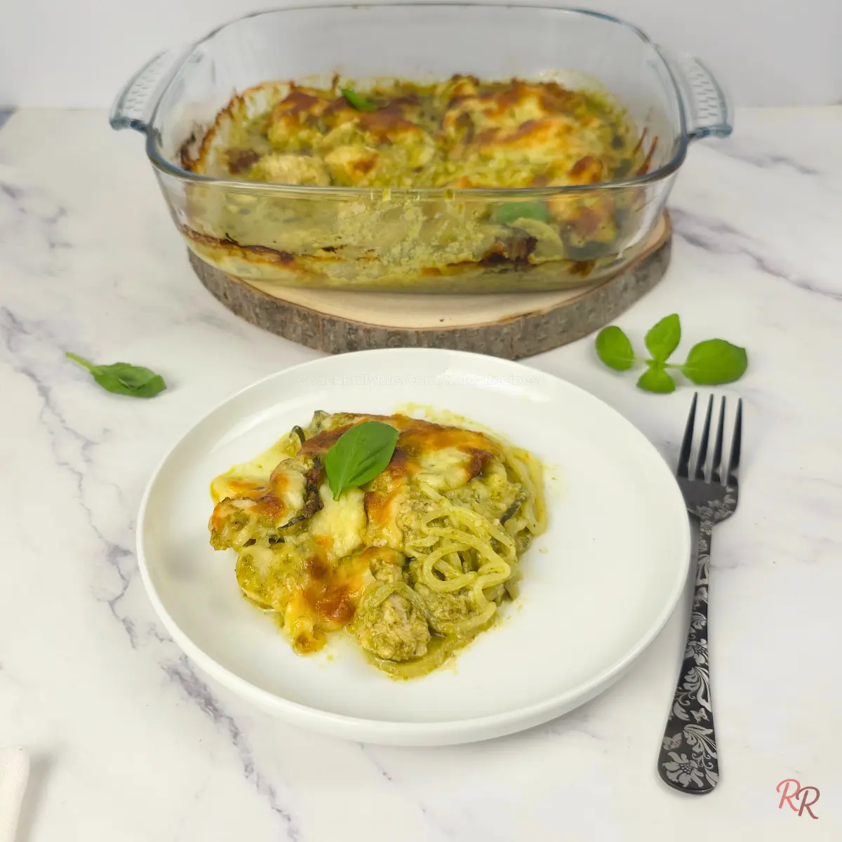 High Protein Low Carb Pesto Chicken Casserole with Zoodle Plated serving of keto pesto chicken casserole with zoodles, cottage cheese, and melted cheese, with casserole dish in background
