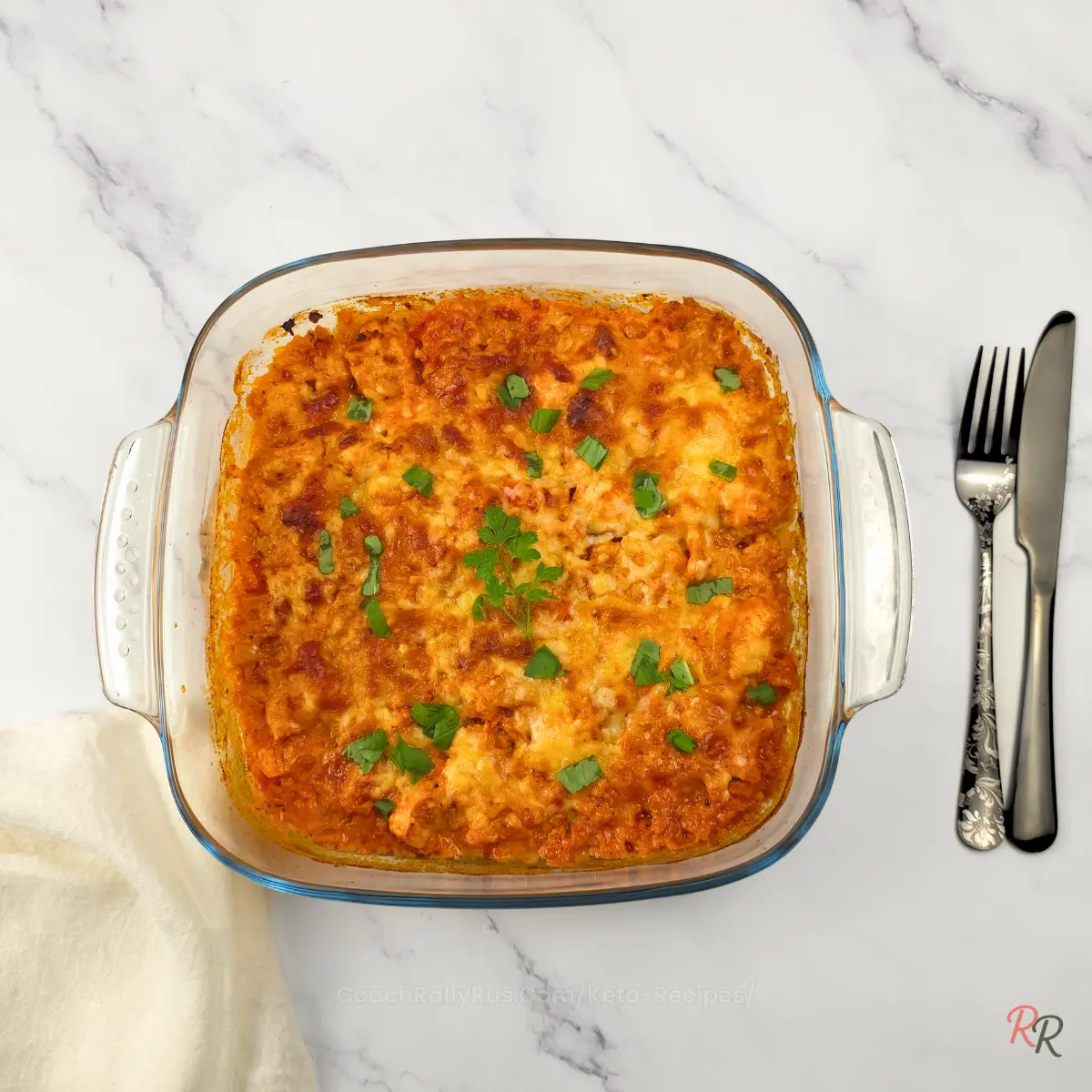 Cheesy Keto Taco Chicken Casserole – Freshly Baked Overhead shot of baked keto taco chicken casserole in a glass dish with melted cheese and fresh herbs.