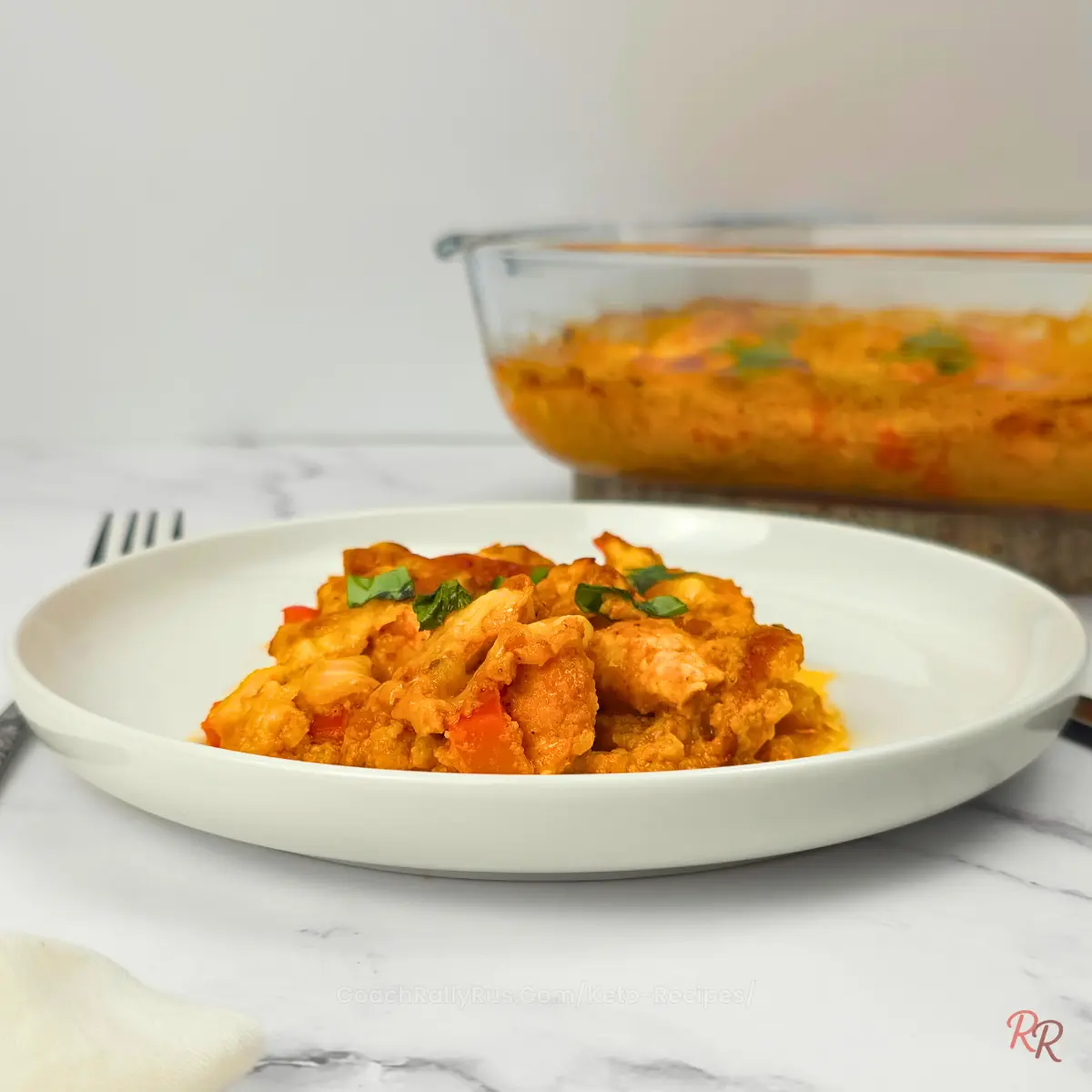 Keto Taco Chicken Casserole - High Protein Low Carb Side view of keto taco chicken casserole on a white plate, glass dish blurred in background.
