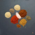Overhead view of taco seasoning spices on slate background.