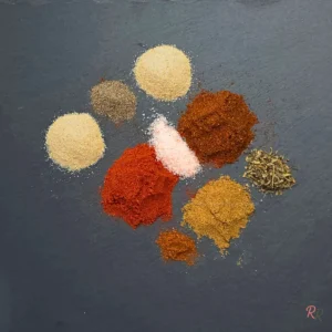 Overhead view of taco seasoning spices on slate background.