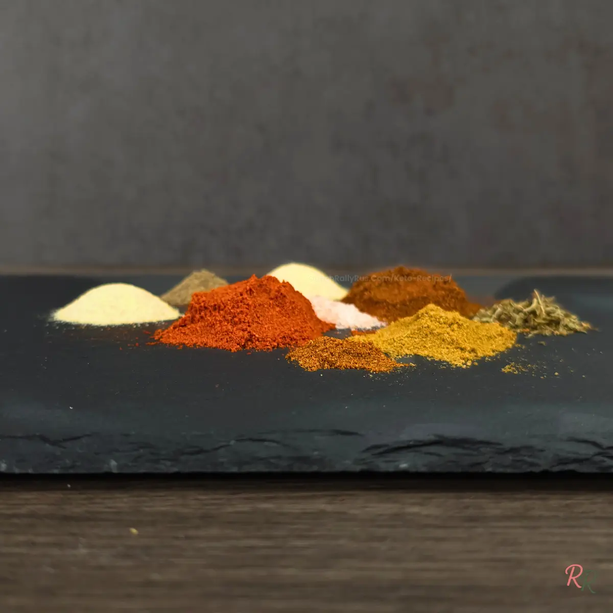 Side view of taco seasoning spices on slate board.