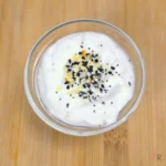 Glass bowl filled with whipped cottage cheese dip topped with everything bagel seasoning.