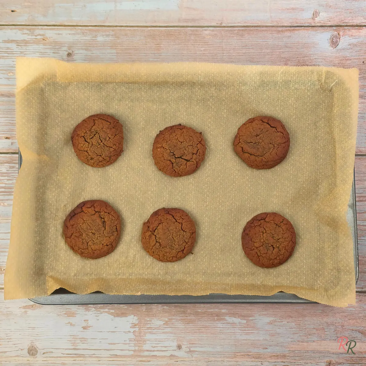 Six plain low carb cottage cheese cookies cooling on a parchment-lined baking tray before adding the tiramisu mousse topping.