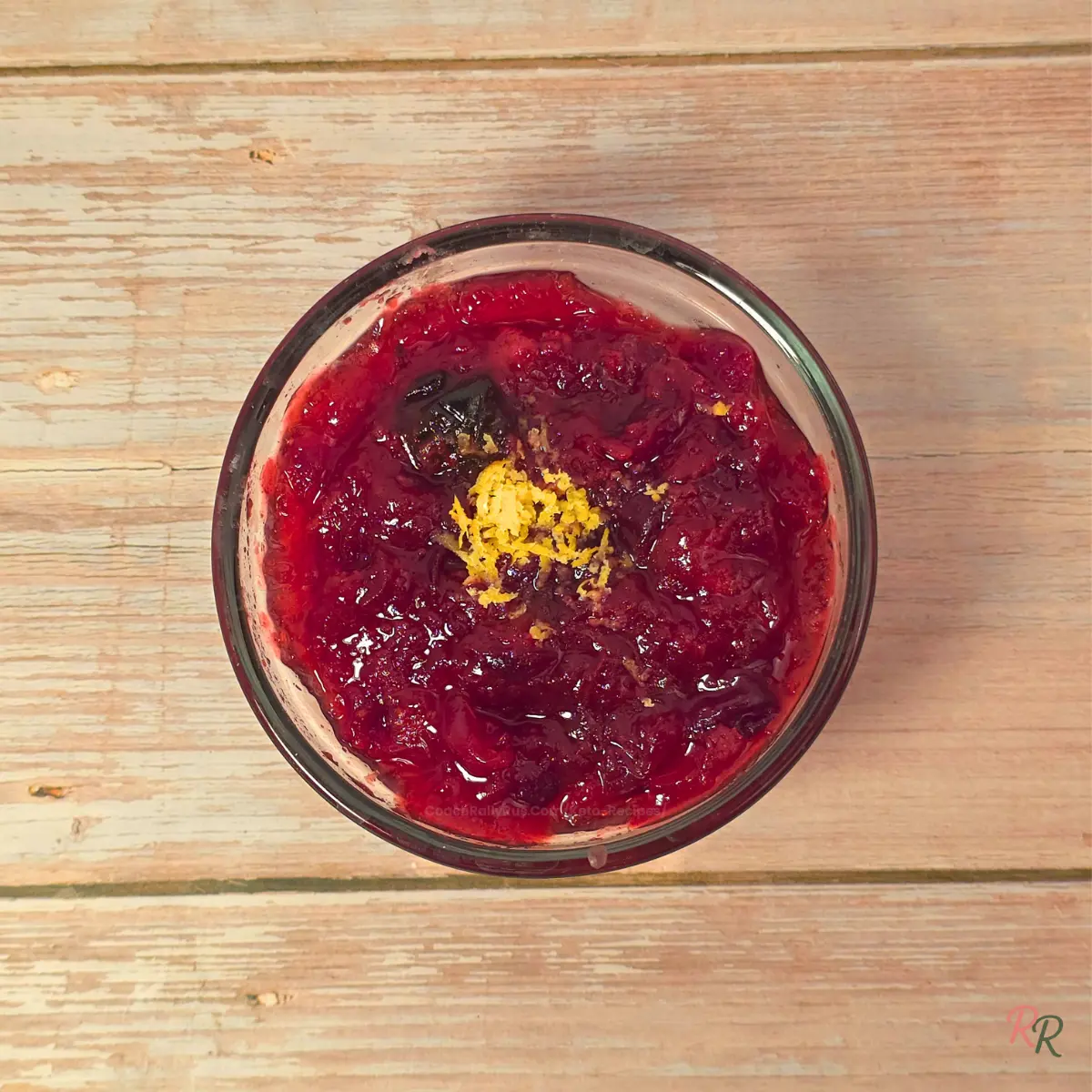 Sugar Free Cranberry Sauce Overhead view of homemade keto cranberry sauce with lemon zest on top in a glass bowl.