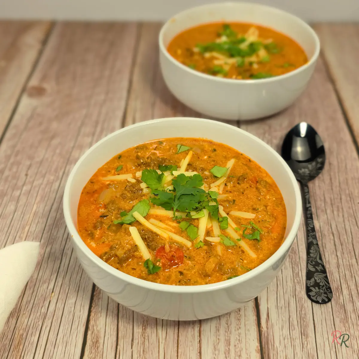 High Protein Keto Cottage Cheese Taco Soup With Ground Beef Close-up of keto cottage cheese taco soup with ground beef, topped with shredded cheese and cilantro, served in white bowls on rustic wood.
