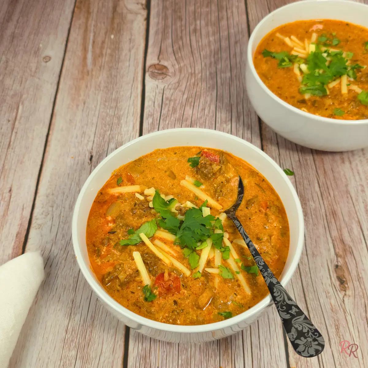 Ground Beef Keto Soup with Cottage Cheese Keto taco soup with ground beef in white bowls, served with a spoon and garnished with cilantro.