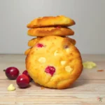 Keto cranberry white chocolate cottage cheese cookies stacked on a wooden board