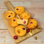 Keto cranberry cottage cheese muffins with pistachios on a wooden board with cranberries and pistachios