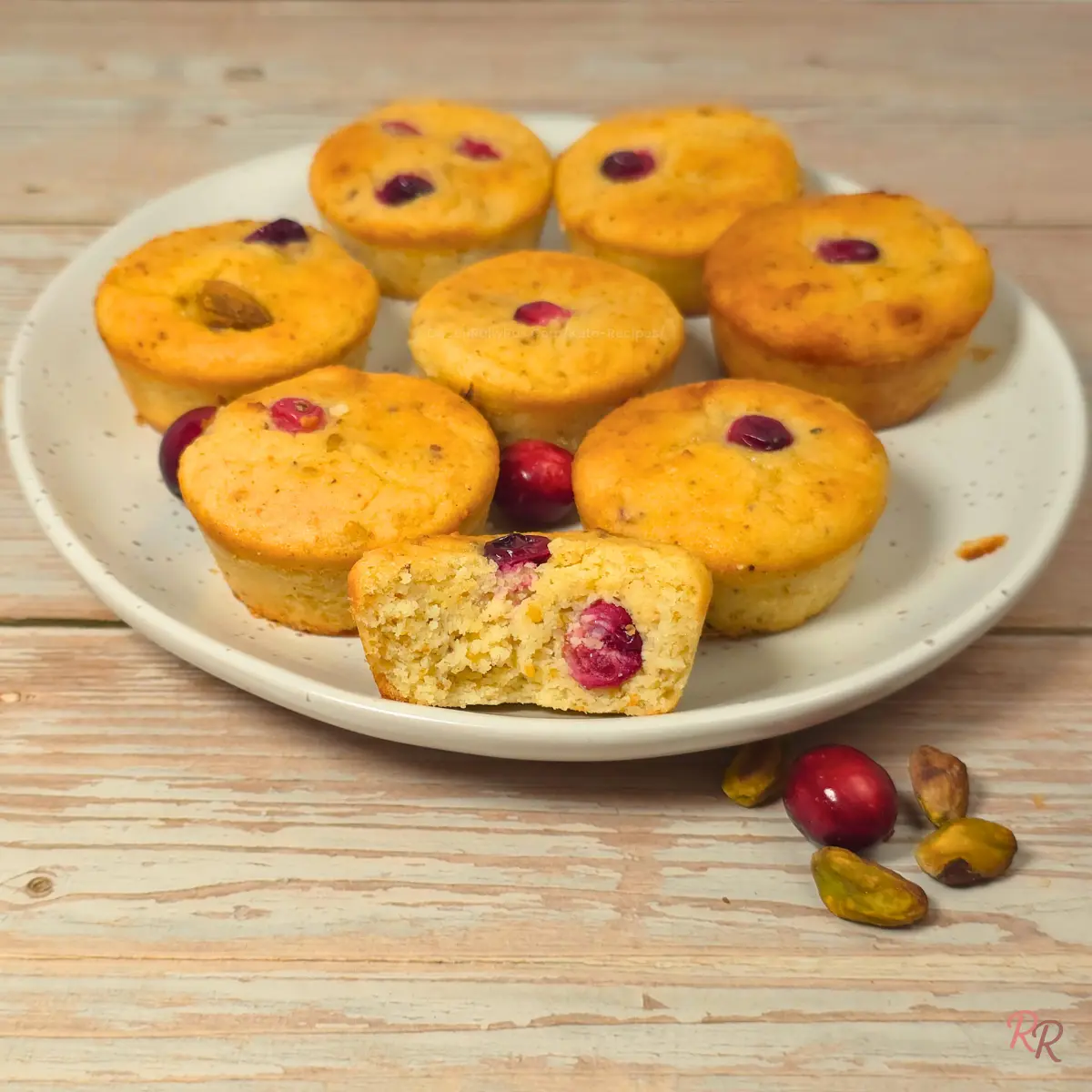 Keto Cranberry Muffins with Cottage Cheese and Pistachios Keto cranberry pistachio cottage cheese muffins on a plate with a cut muffin in front