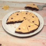 Keto cottage cheese brownie peanut butter pizza sliced on a plate, showing a soft chocolate brownie base with creamy peanut butter topping