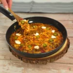Hand lifting a cheesy bite from a keto Italian cheeseburger cottage cheese skillet in a black pan