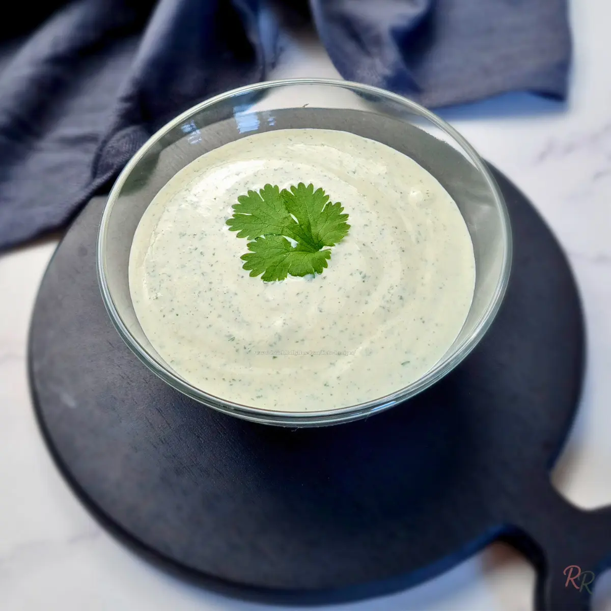 High Protein Keto Cottage Cheese Ranch Dip Glass bowl of high protein keto cottage cheese ranch dip topped with parsley on a black serving board