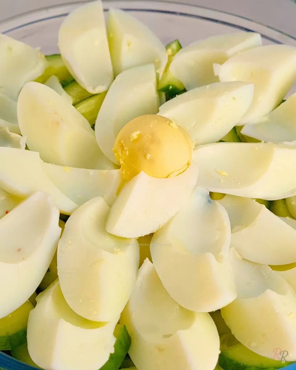 Quartered hard-boiled eggs over sliced cucumber in a bowl for keto egg salad without mayo