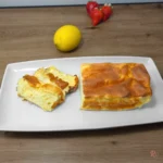 Sweet cottage cheese bread loaf with sliced pieces showing golden crust and soft airy interior on a white plate with strawberries and lemon