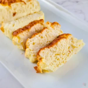 Sliced 2 ingredient cottage cheese and egg bread on a white plate showing the fluffy interior texture of each slice