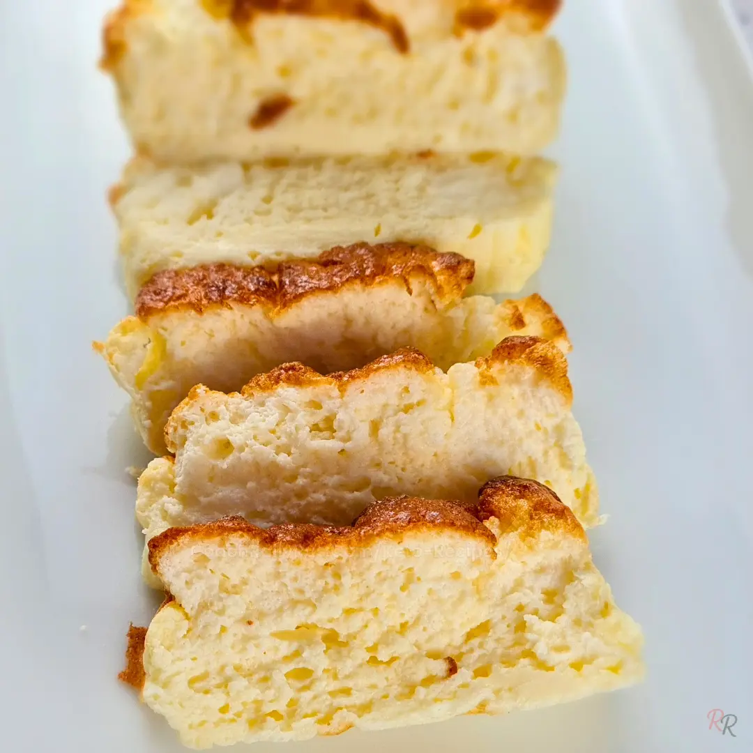 Close-up of keto cottage cheese bread slices lined up in a row on a white plate showing the soft airy interior texture