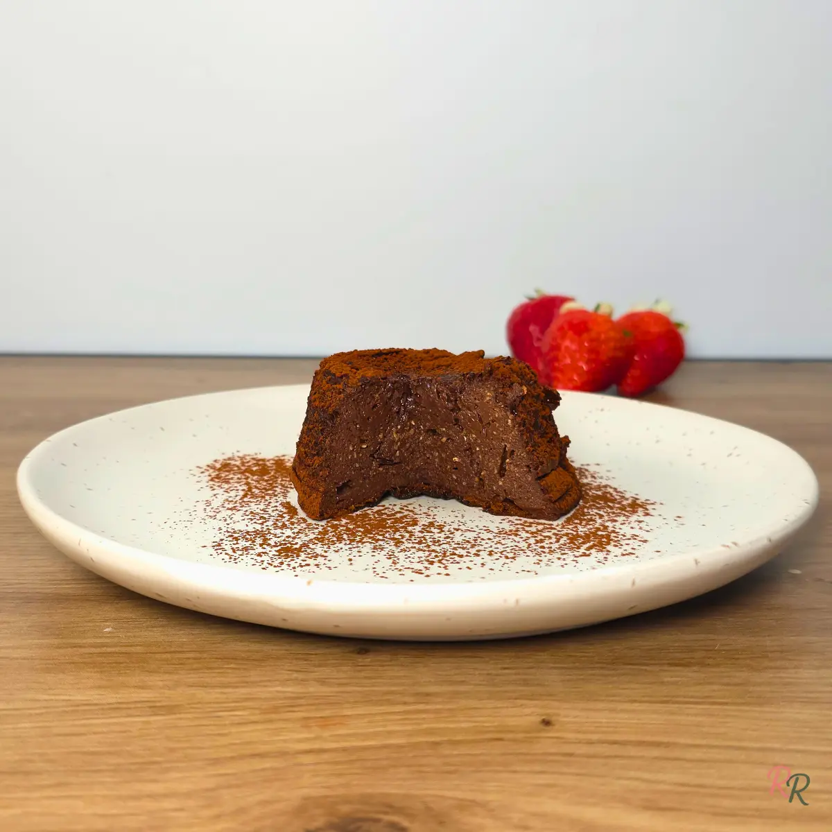 Sliced tiramisu cottage cheese mug cake on a cream plate showing the dense moist interior with fresh strawberries in the background